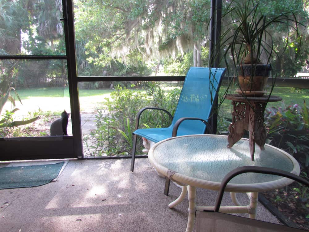 screened enclosed patio small glass top table and metal blue chair