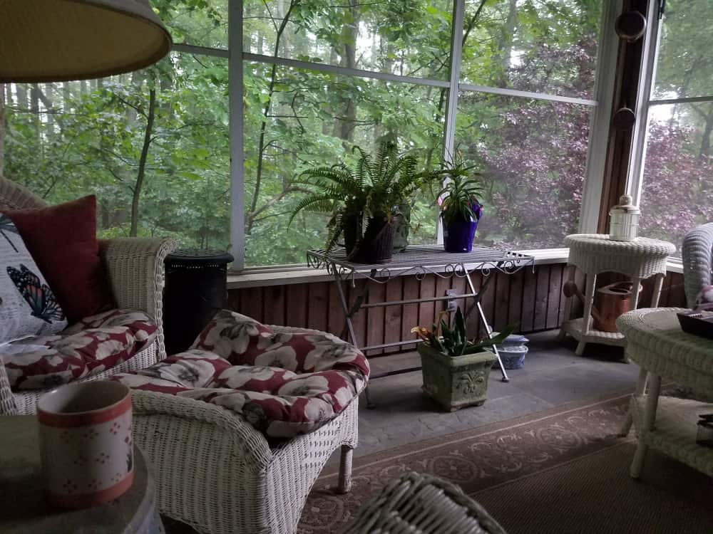 small enclosed patio glass windows wicker furniture pot plants 