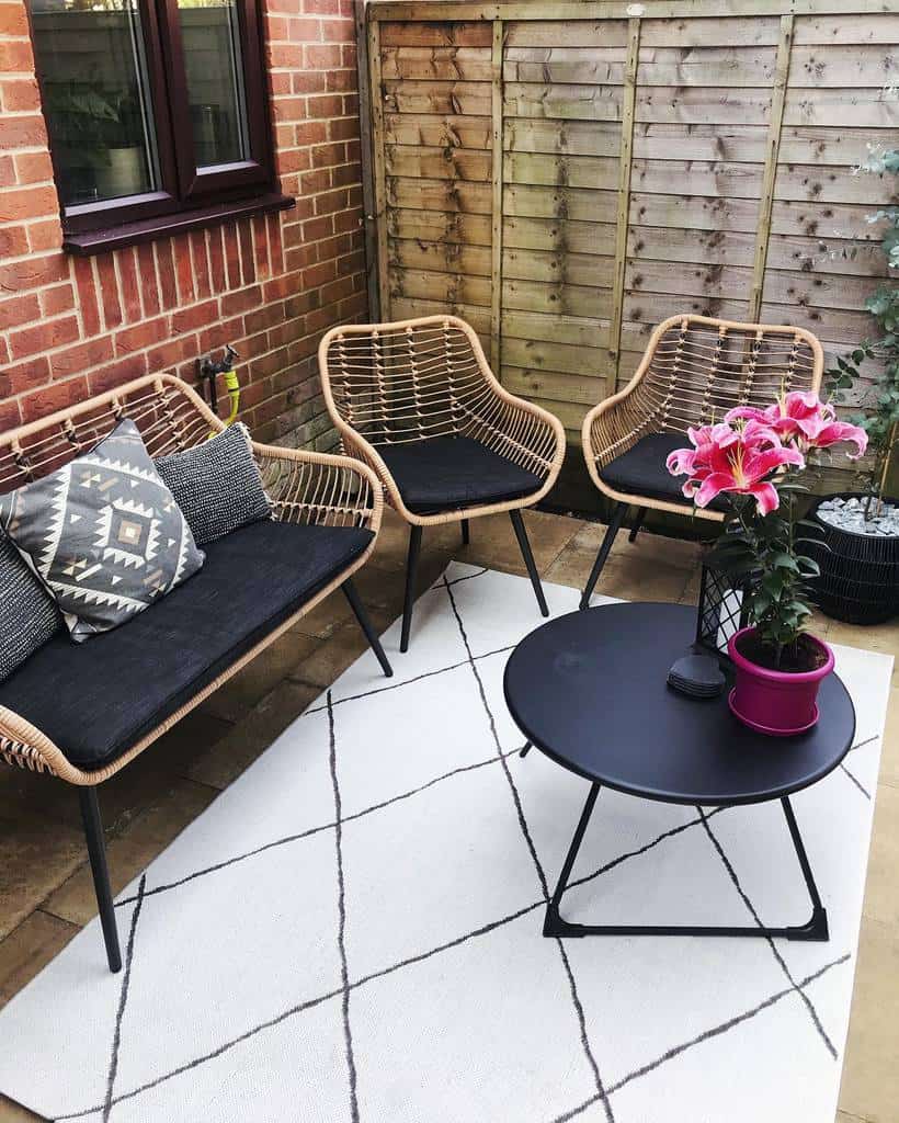 enclosed patio stone pavers wood fence wicker furniture small black table 