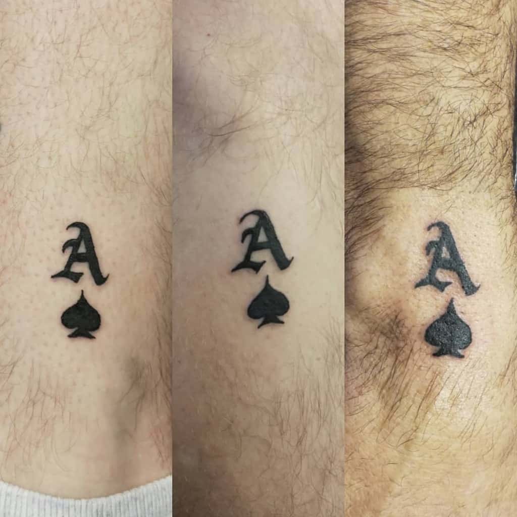 A simple black tattoo of the Ace of Spades symbol, featuring the letter "A" above the spade
