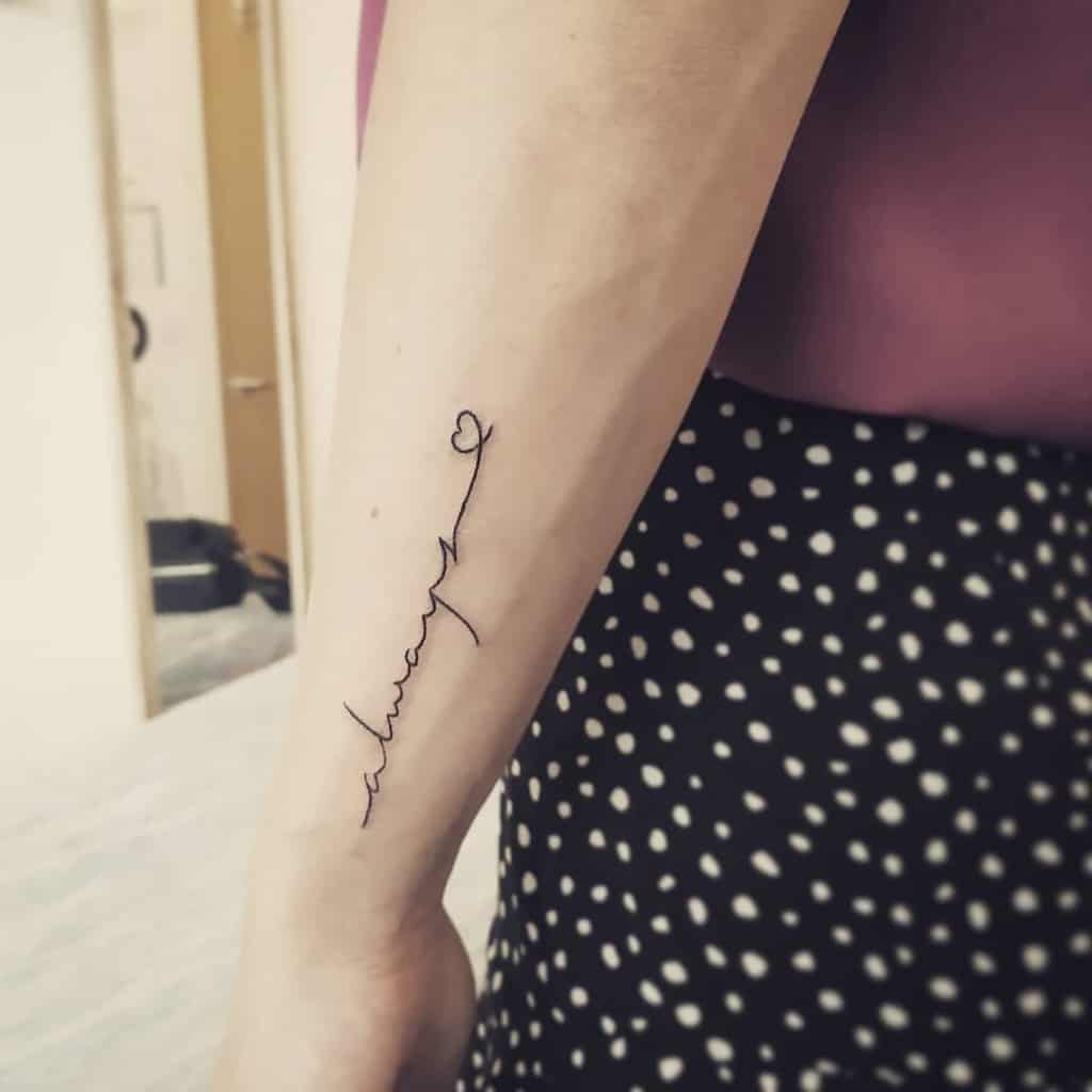 Minimalist forearm tattoo with 'always' written vertically in delicate cursive, ending with a heart, symbolizing eternal love