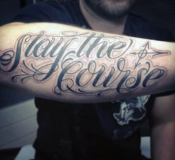 Tattoo on forearm that reads "Stay the Course" with decorative script and small arrow