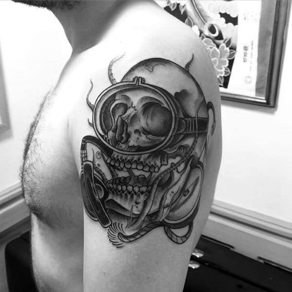 Detailed black and grey tattoo of a scuba diving skull with goggles and breathing gear on upper arm.