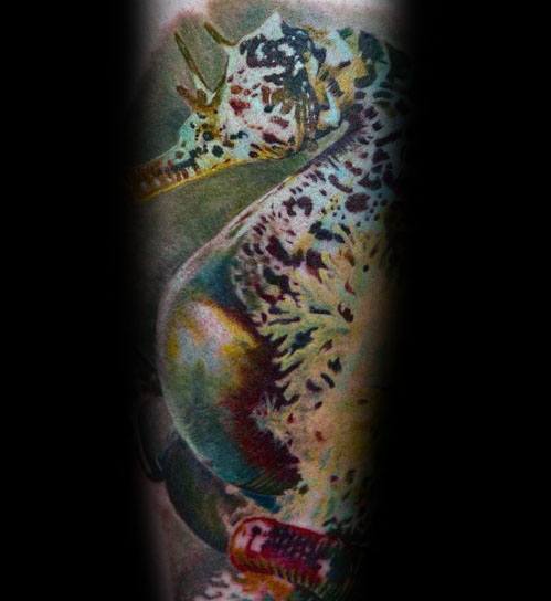Hyper-realistic seahorse tattoo on forearm, featuring intricate textures, lifelike colors, and detailed shading for a vivid underwater effect.