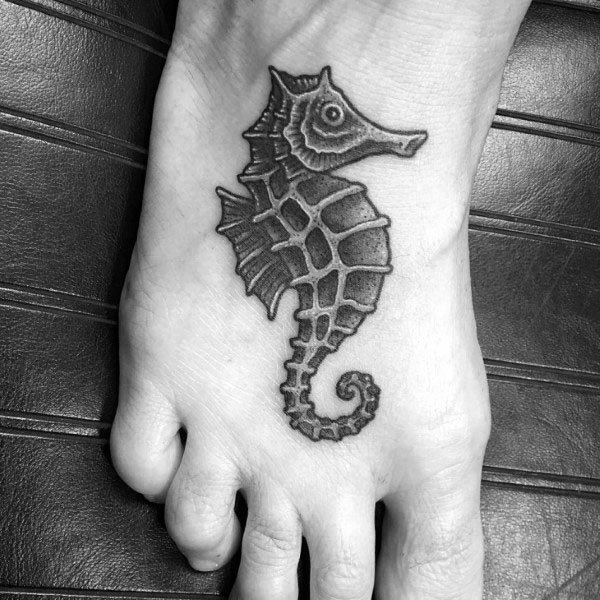 Black and grey seahorse tattoo on foot, featuring fine shading and bold outlines for a detailed and textured marine-inspired design.