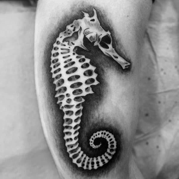 Black and grey seahorse skeleton tattoo on arm, featuring bold shading and intricate bone details for a striking and realistic design.