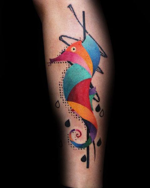 Abstract watercolor seahorse tattoo on forearm, featuring bold geometric shapes, vibrant colors, and artistic black ink elements for a unique design.