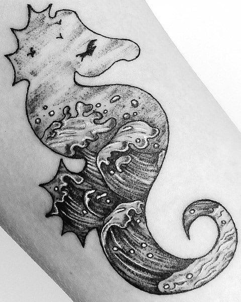 Black and grey seahorse tattoo on forearm, featuring ocean wave details within its body, creating a unique fusion of marine life and water elements.