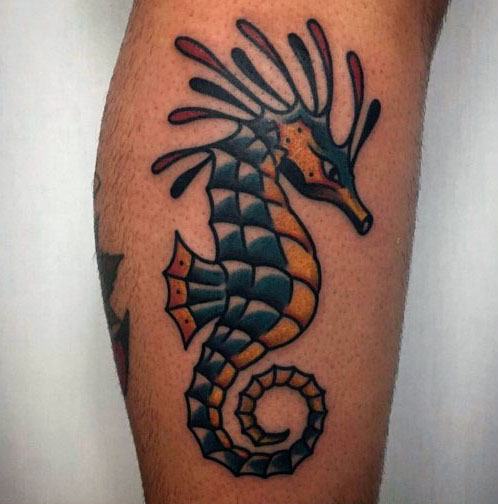 Neo-traditional leafy seadragon tattoo on leg, featuring bold outlines, vibrant blue and orange hues, and stylized details for a striking marine design.