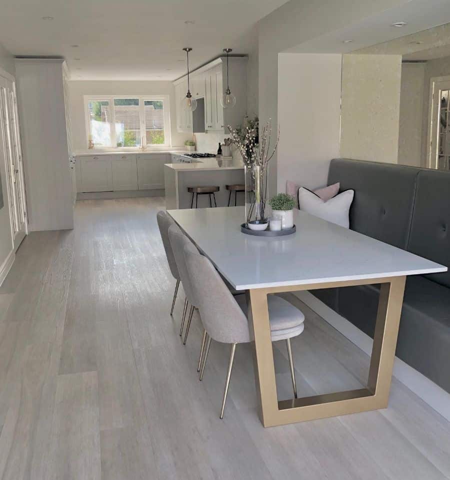 Modern and spacious kitchen and dining area with sleek white table, banquette seating, and neutral tones.