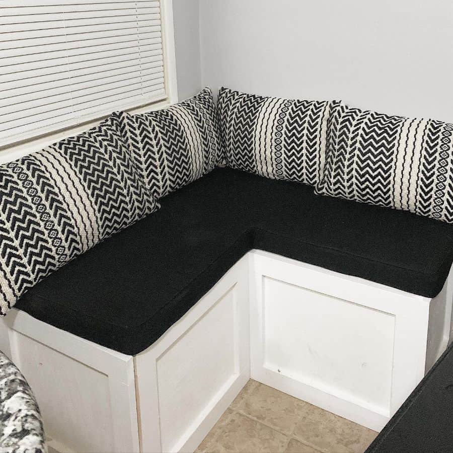 Black and white corner seating area with patterned pillows and built-in bench.