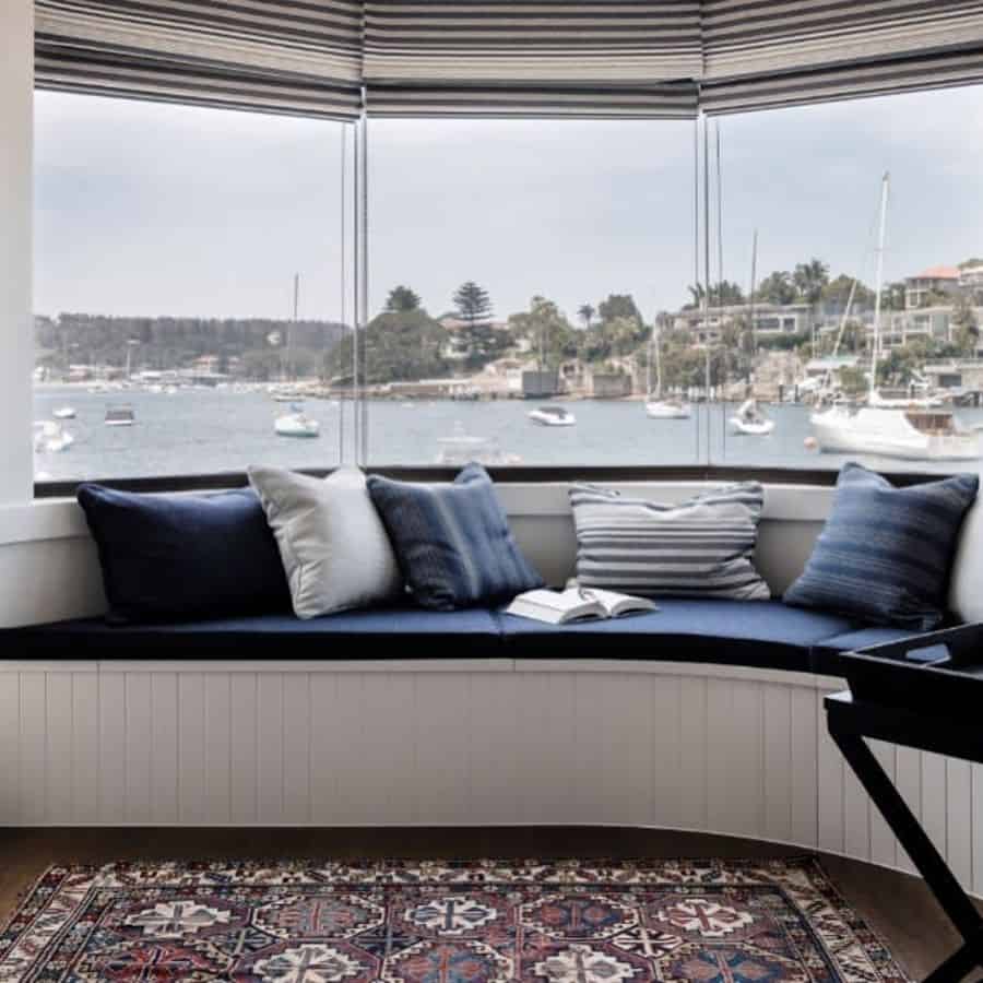 Cozy bay window seating with a marina view, navy cushions, and striped window shades.