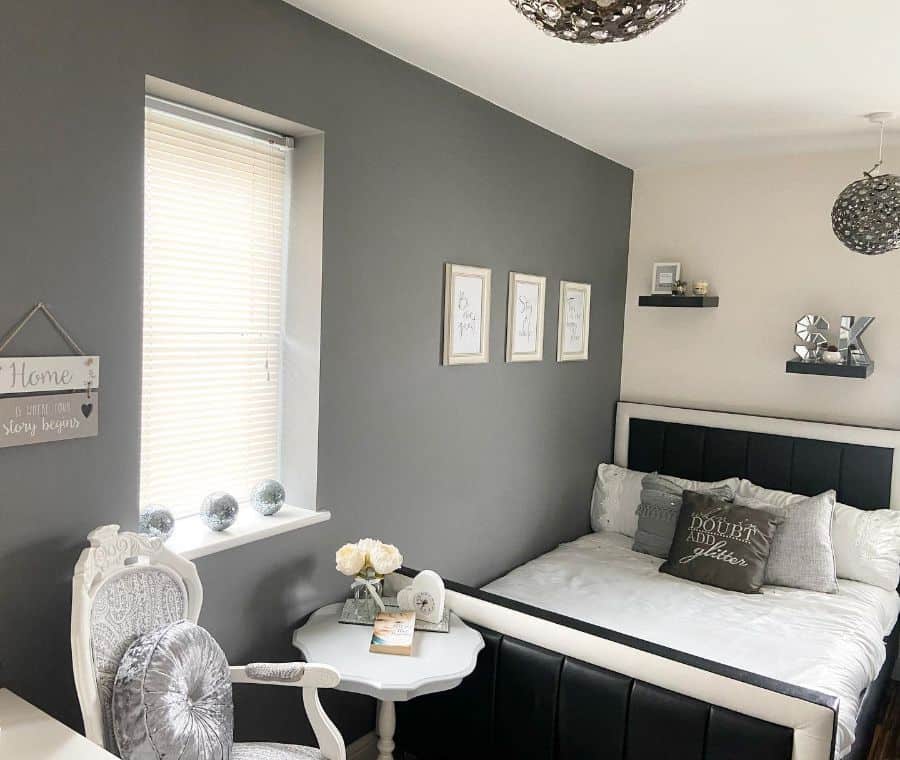gray feature wall main bedroom large black bed frame white accent chair and table