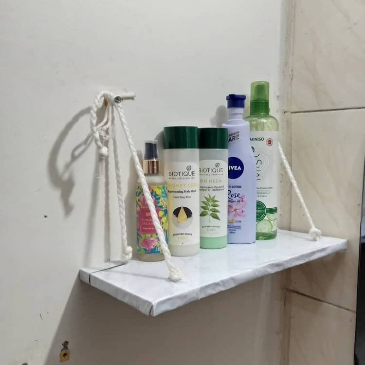 Small hanging bathroom shelf with skincare products and body lotions.