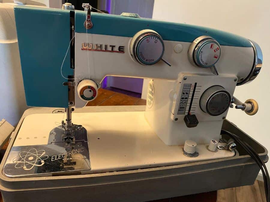 Vintage sewing machine with blue and white design, featuring dials and a foot pedal