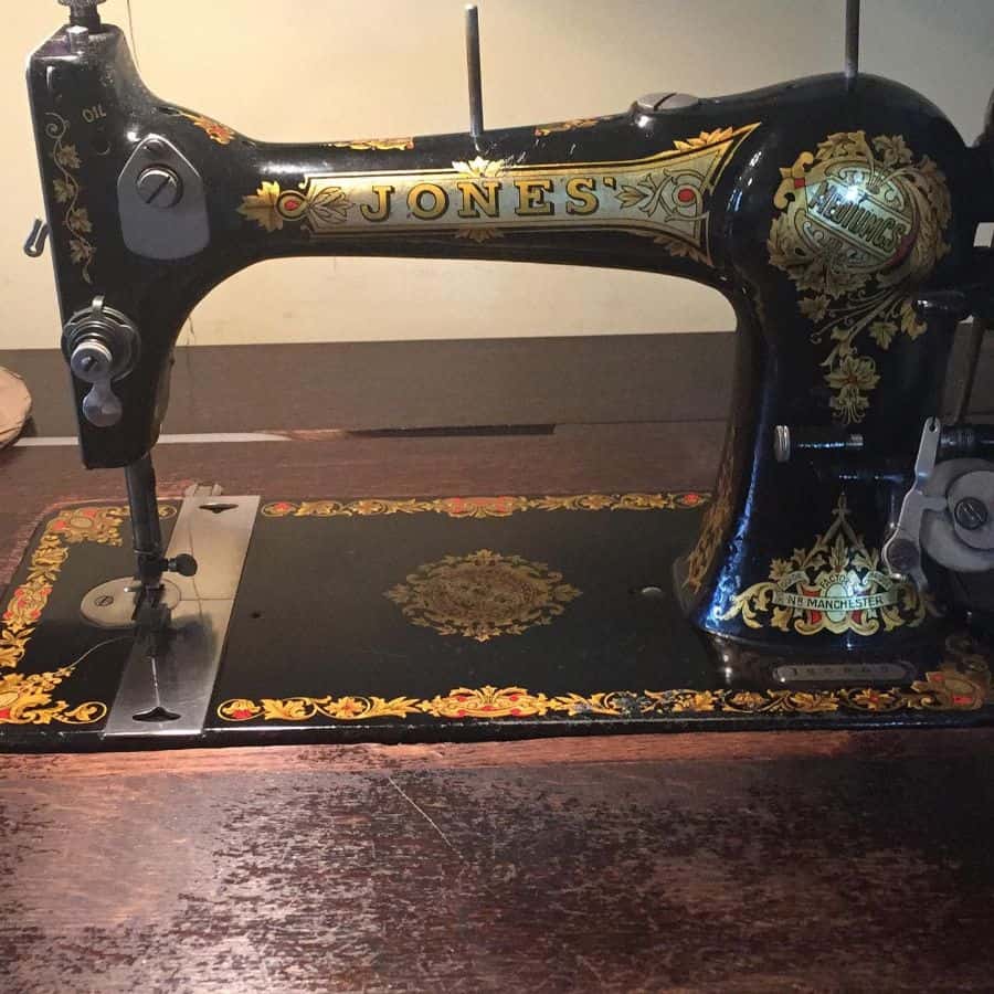 Vintage black sewing machine with ornate gold details on a wooden table
