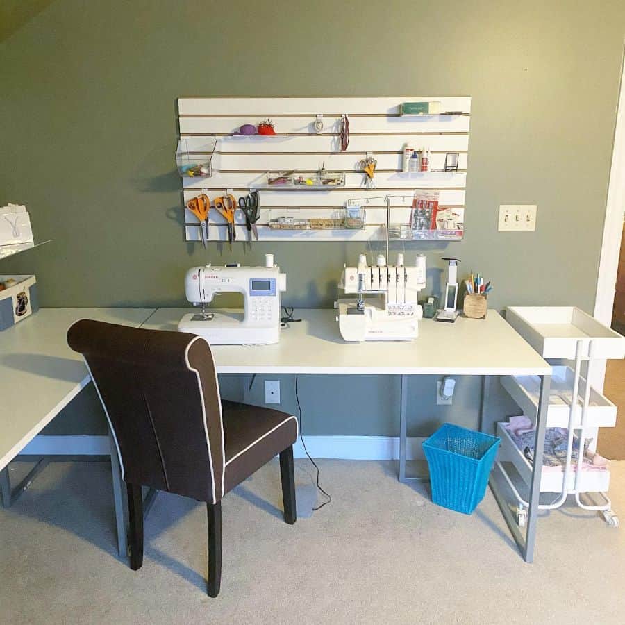 Organized sewing desk with machines, wall-mounted storage for tools, and a rolling cart for easy access to supplies
