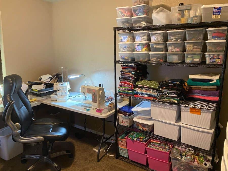 Efficient sewing setup with organized storage shelves, fabric stacks, labeled bins, and a well-lit workstation