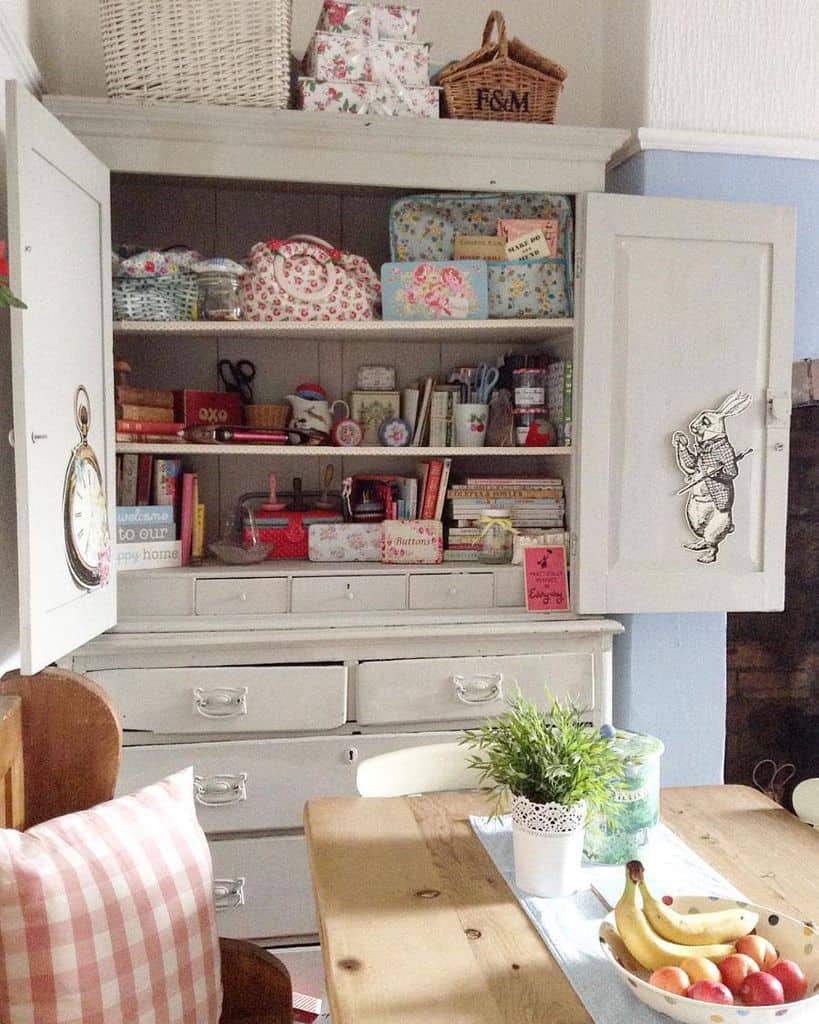 Charming vintage storage cabinet repurposed for sewing essentials, featuring floral fabric bins, craft supplies, and a cozy cottage aesthetic