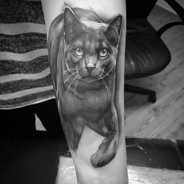 Hyper-realistic black cat tattoo on the forearm, featuring detailed fur shading and intense eyes for a bold and lifelike design.