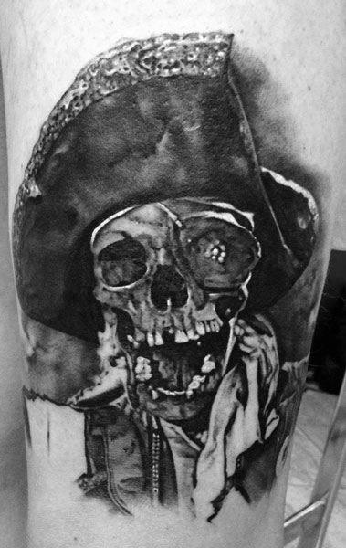Black and gray realistic tattoo of One-Eyed Willy from The Goonies, featuring a detailed skull wearing a pirate hat and tattered clothing.