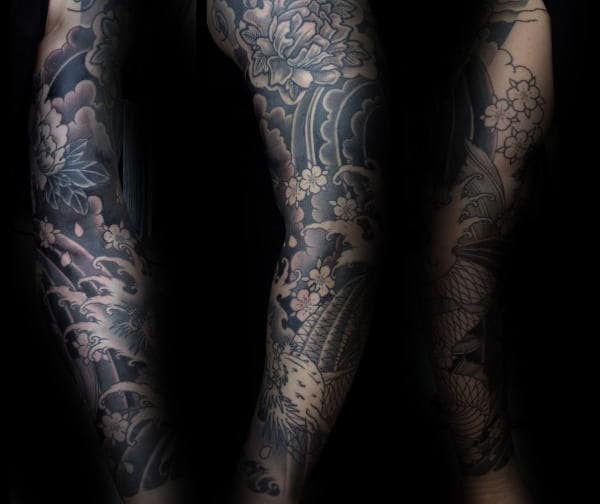 Japanese full sleeve tattoo in black and grey, featuring cherry blossoms, waves, and intricate floral patterns for a bold yet elegant look