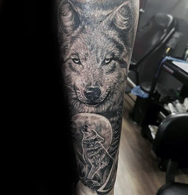 Detailed black and grey wolf tattoo with a howling wolf and full moon on forearm