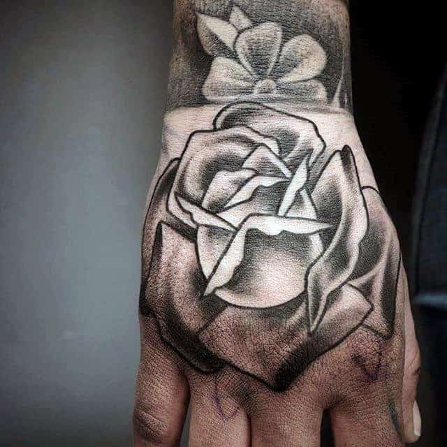 Black and gray rose tattoo on a person's hand