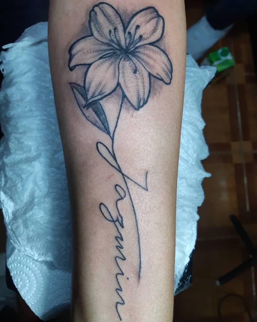 Tattoo of a jasmine flower with the word "Jazmin" on a forearm