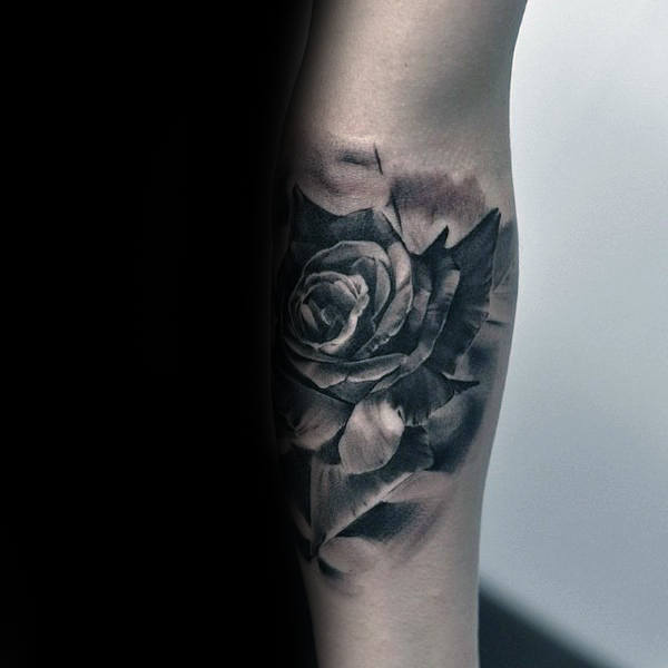 Tattoo of a realistic black and gray rose on a forearm