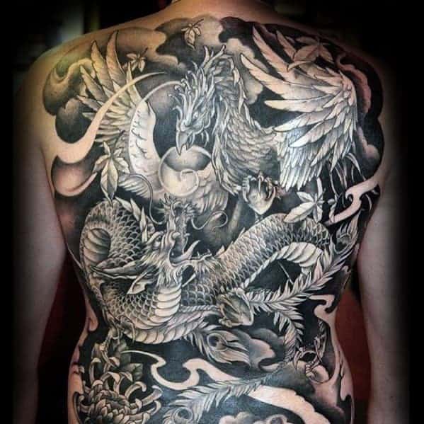 Traditional Japanese full-back tattoo featuring a dragon and phoenix in a dynamic battle, detailed with smoke and clouds