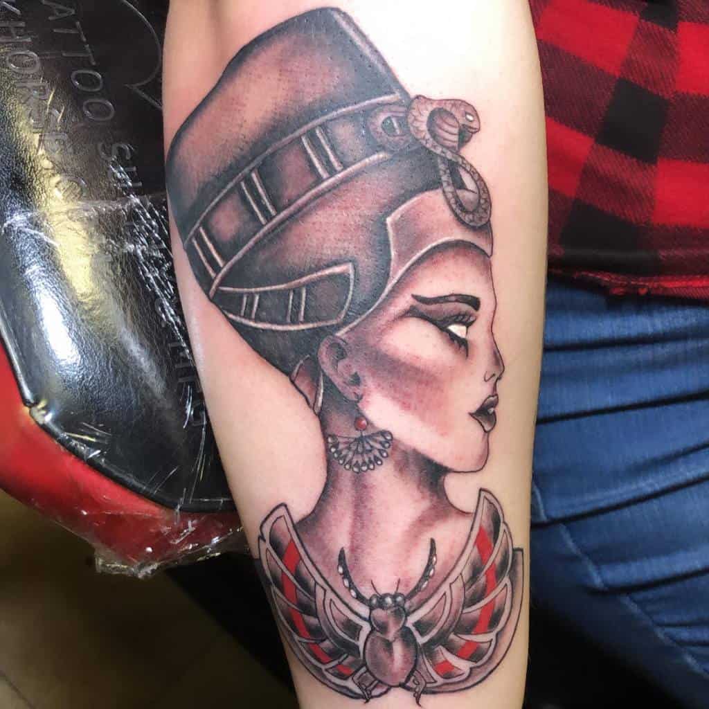 Tattoo of Nefertiti with a headdress and scarab design on an arm