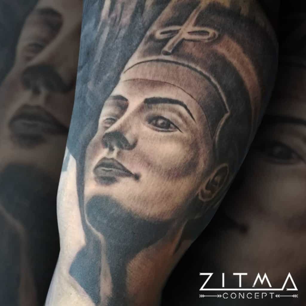 Tattoo of ancient Egyptian Pharaoh Nefertiti on an arm, showing detailed facial features and traditional headdress