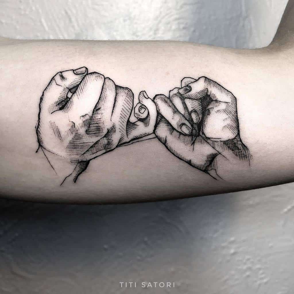 Tattoo of two hands intertwining pinky fingers on an arm