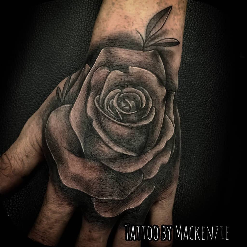 A captivating black and gray rose tattoo elegantly graces the hand
