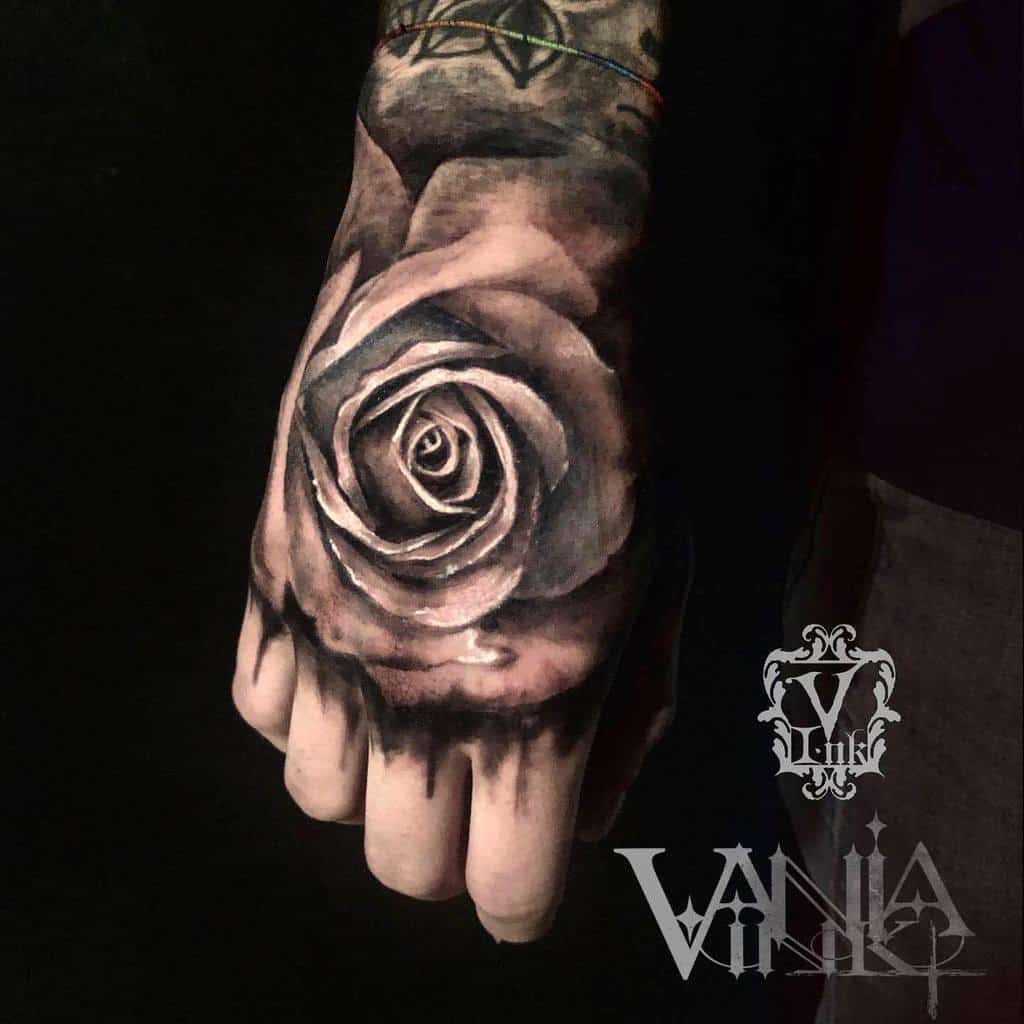 A stunningly realistic rose tattoo graces a person's hand, showcasing intricate shading and meticulous details