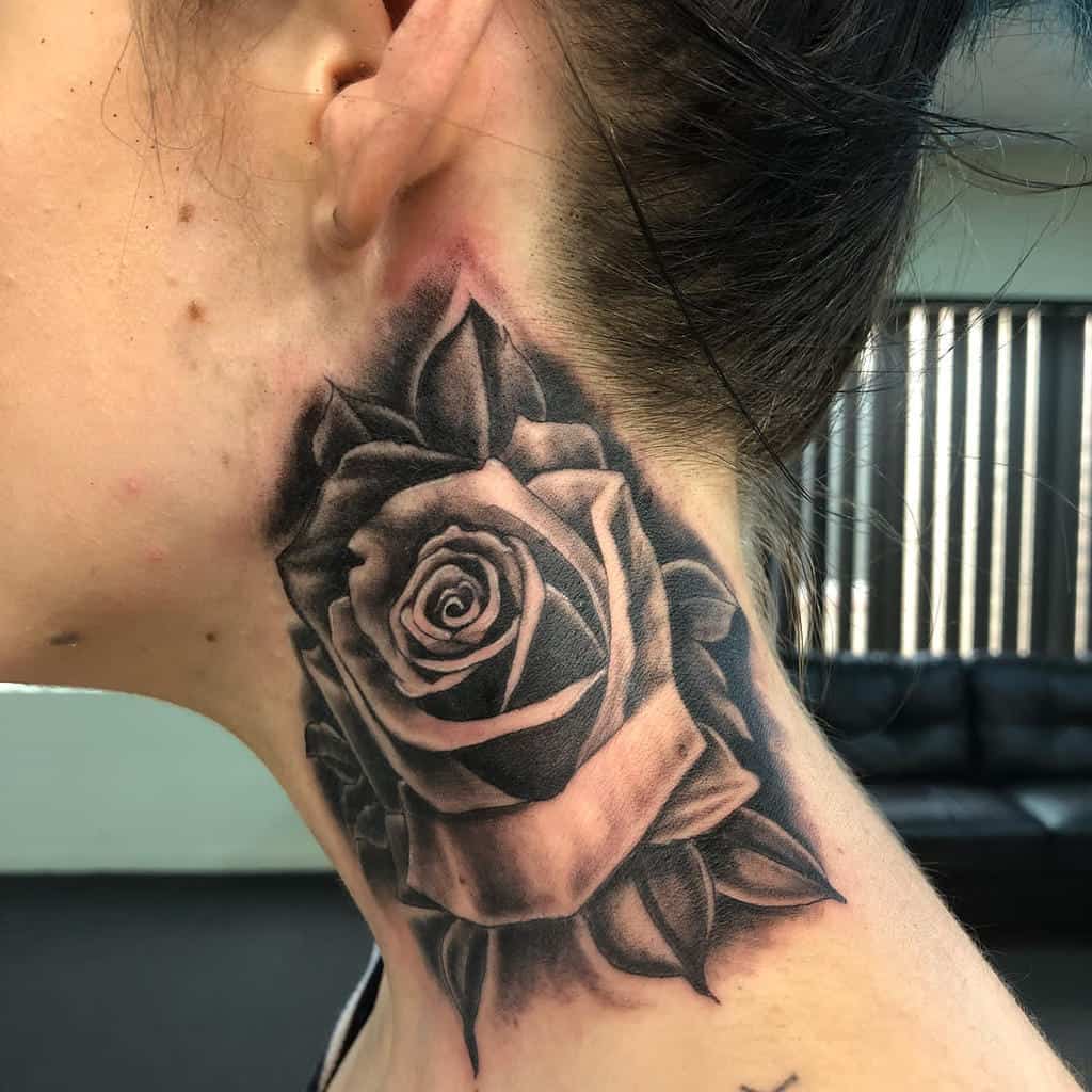 Black and gray rose tattoo elegantly adorning the side of a person's neck