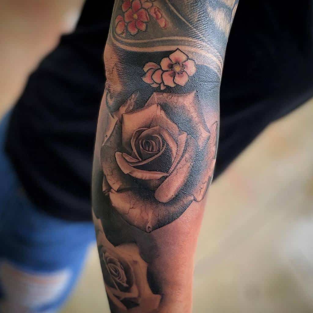 Tattooed arm with detailed roses and small blossoms