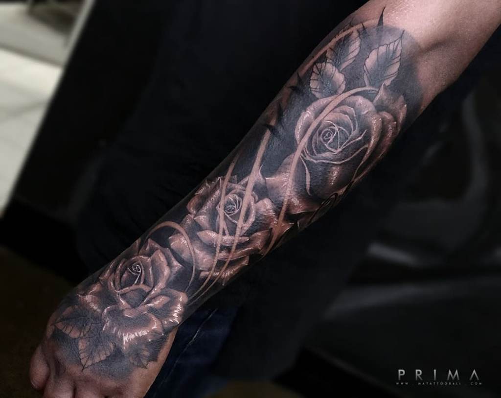 Forearm tattoo with detailed roses and leaves in grayscale shading