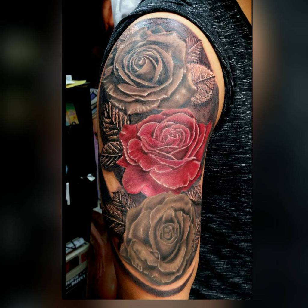 Tattoo sleeve featuring three roses on an arm, with two in black and one strikingly red