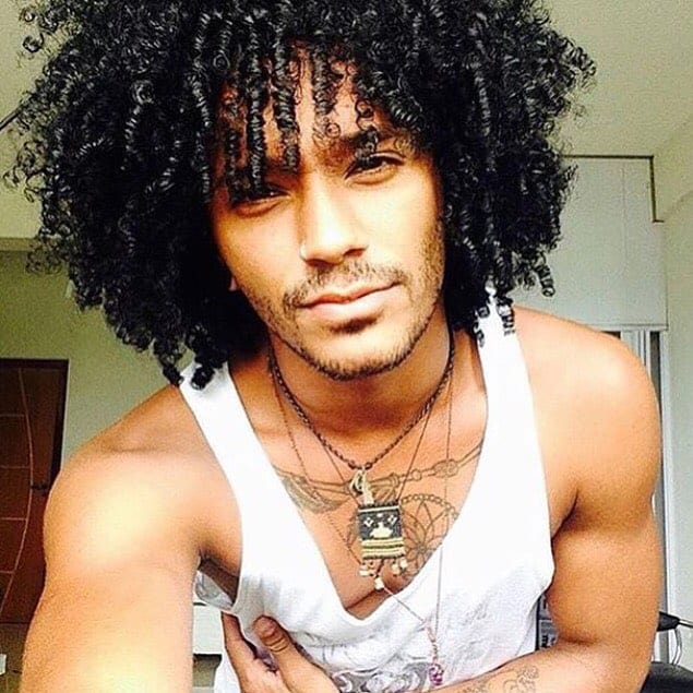 A man wearing a mid-length curly hair with a lot of volume and texture