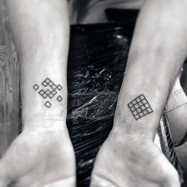 Two forearms with geometric tattoos consisting of squares and diamonds