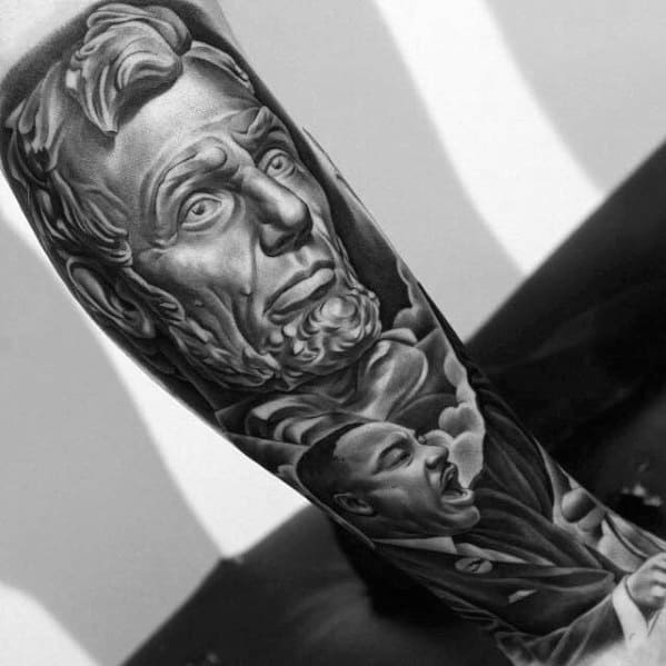 Tattoo of Abraham Lincoln and Martin Luther King Jr. in black and gray on an arm