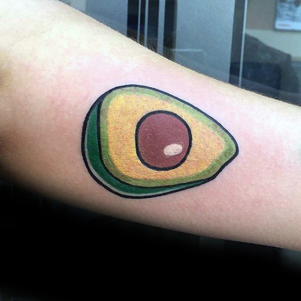 Bright and simple avocado tattoo on the arm with bold black outlines and solid green, yellow, and brown coloring for a playful look.