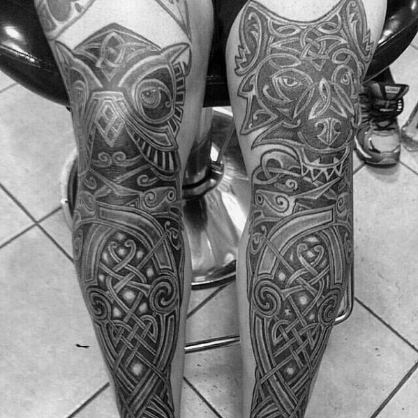 Celtic wolf and owl tattoos on calves with detailed knotwork, tribal patterns, and symmetrical designs wrapping around both legs.