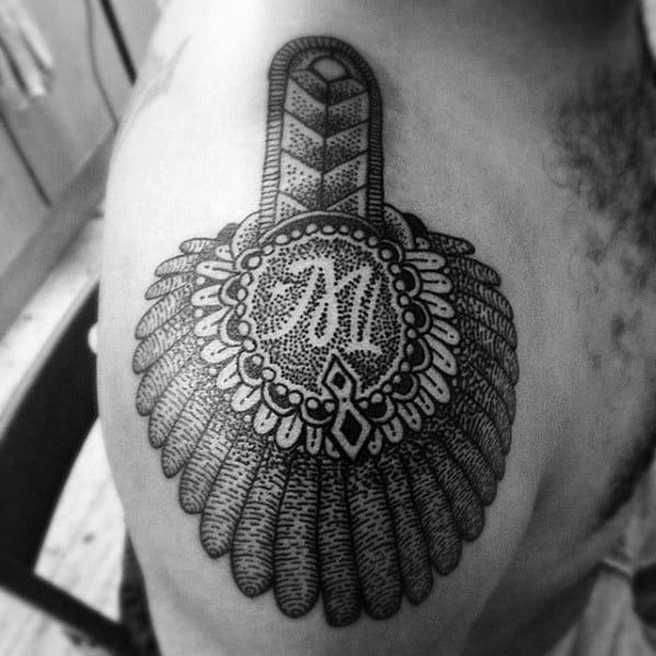 Dotwork epaulette tattoo with ornamental patterns, a central monogram, and scalloped tassels layered over the shoulder.