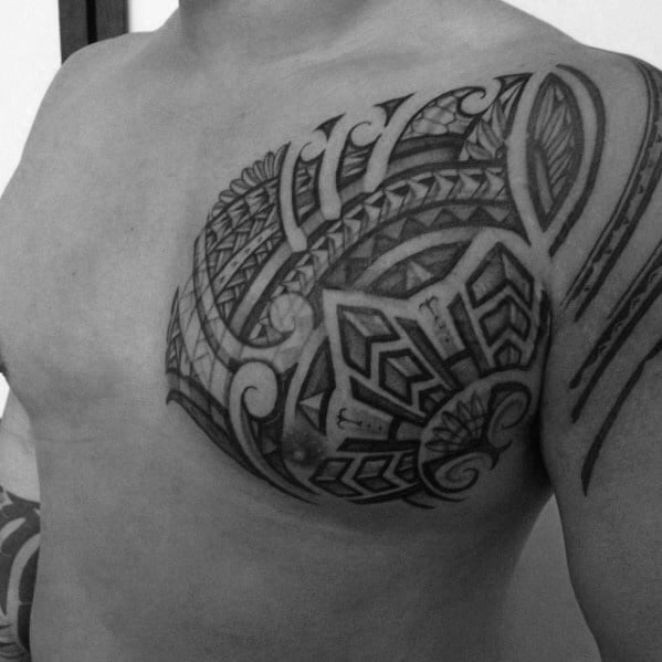 Filipino tribal chest tattoo with bold geometric shapes, flowing lines, and layered patterns extending toward the shoulder and upper arm.