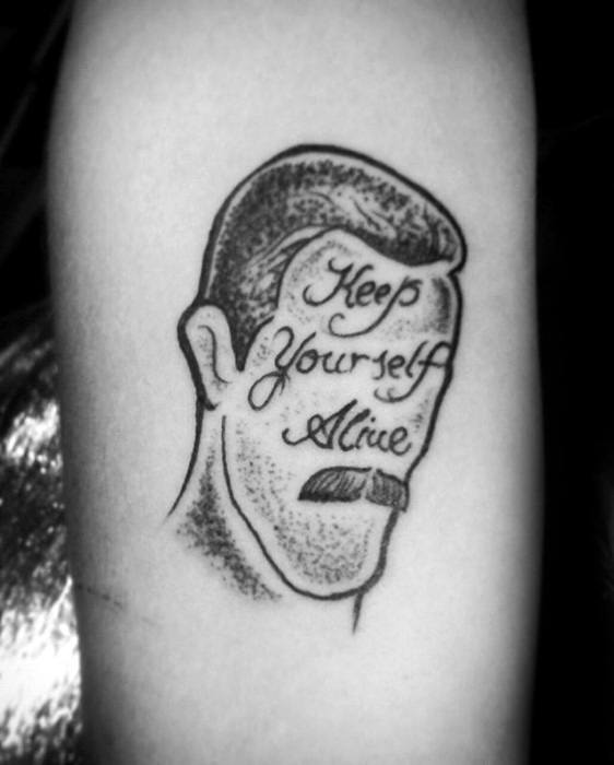 Minimalist black ink tattoo of Freddie Mercury’s face outline with “Keep Yourself Alive” written inside, styled with fine dotwork shading.