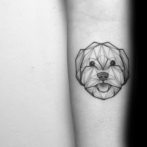 Minimalist geometric dog face tattoo with clean linework, showcasing a happy expression and tongue out on the inner forearm.