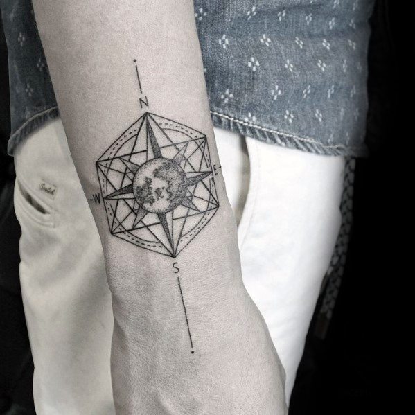 Geometric compass tattoo on forearm with world map center and fine linework, combining global and directional symbolism.